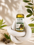 Bottle of GDR Anti Dandruff Oil on a white stone surface with green leaves in the background
