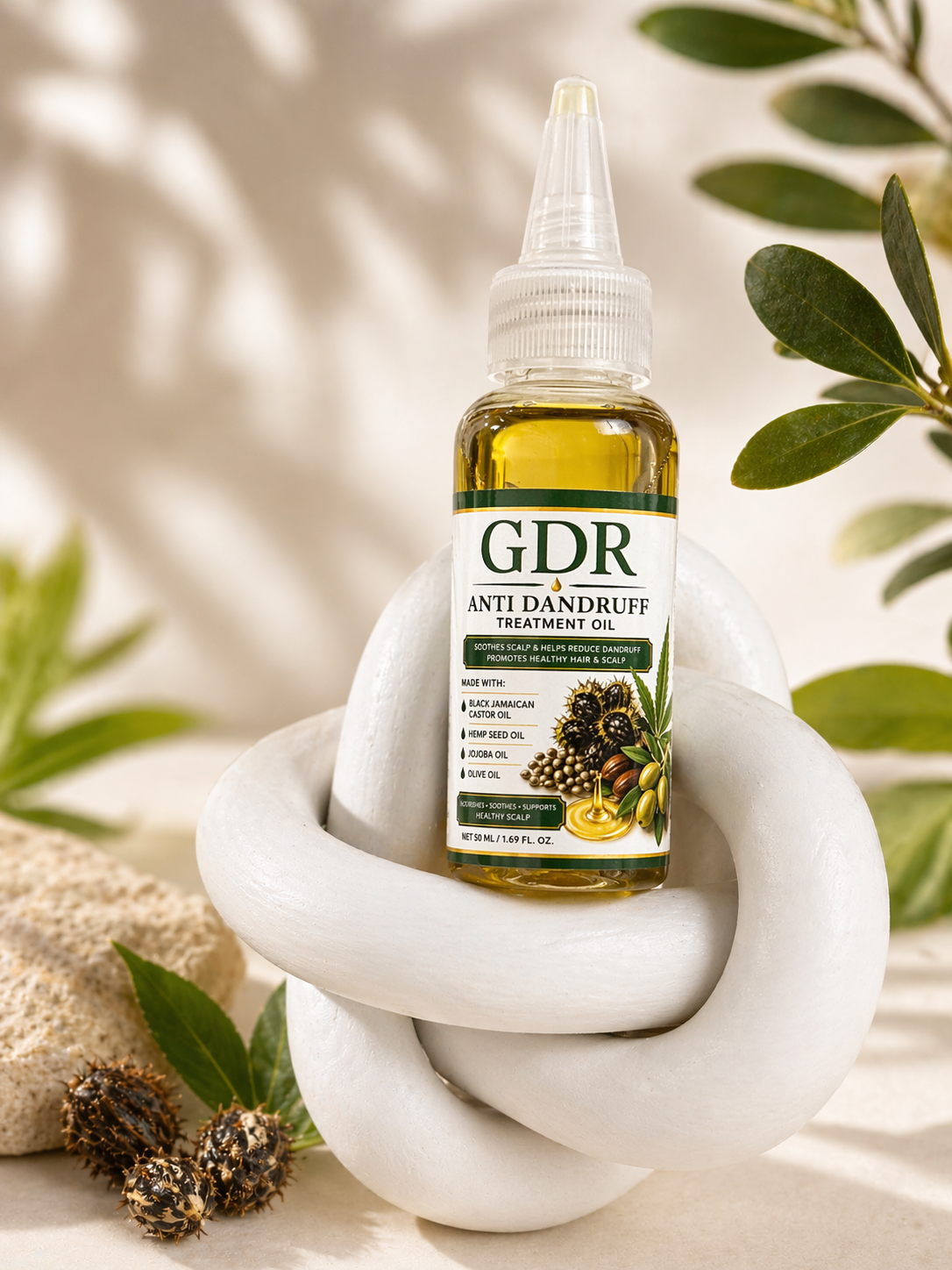 Bottle of GDR Anti Dandruff Oil on a white stone surface with green leaves in the background