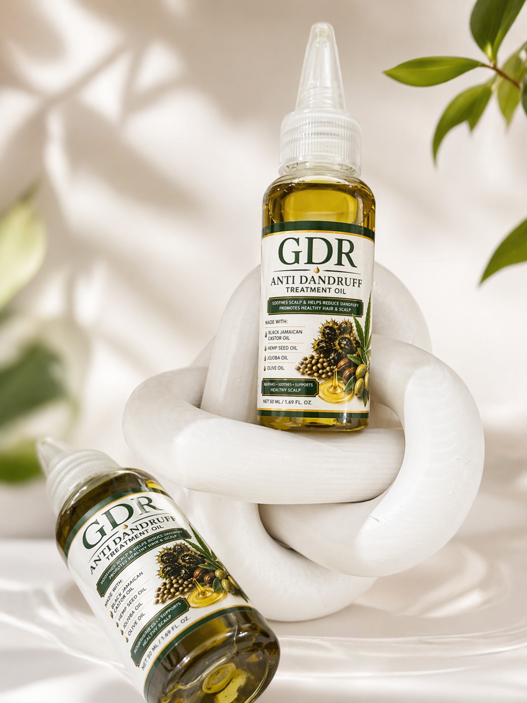 GDR Anti Dandruff Treatment Oil bottles held by a hand with a soft background